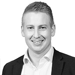 A black and white photo of a man smiling.