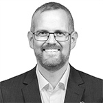 A black and white photo of a man wearing glasses and a suit.