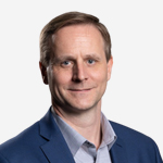 Craig Thomson A man in a blue suit is smiling for the camera.