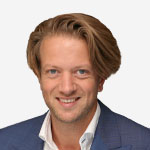 A man in a blue suit smiling for the camera.